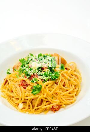 Spaghetti mit getrockneten Tomaten, Hühnerfleisch, Parmesan und mit Petersilie bestreut. Stockfoto