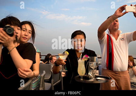 Kellnerin mit Cocktails in der Hand. Banyan Tree auf dem Dach Vertigo & Moon Bar, Restaurant, Bangkok, Thailand. Blick auf die Stadt, Stockfoto
