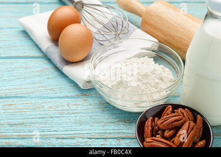 Backzutaten mit Mehl Eiern Pecan-Nüssen Milch auf Holztisch Stockfoto