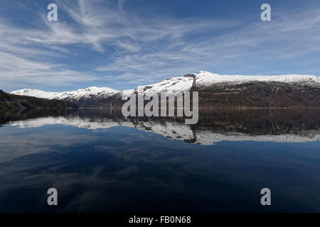 Symmetrische Reflexion von Schnee bedeckt Berge rund um den Hardangerfjord in Westnorwegen. Stockfoto