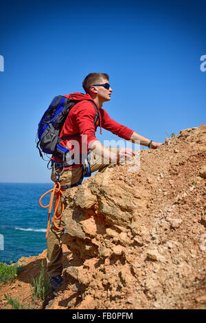 touristischen klettert auf einer Klippe über blauen Himmelshintergrund Stockfoto