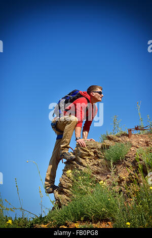 Mann klettert auf einer Klippe über blauen Himmelshintergrund Stockfoto