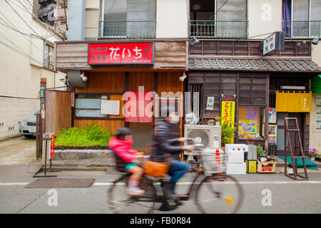 Japanische Eltern mit einem Kind auf dem Rücksitz Radfahren Stockfoto