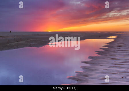 Sonnenuntergang Farben spiegelt sich in ein Gezeitenbecken an einem Strand auf der Insel Texel in den Niederlanden. Stockfoto