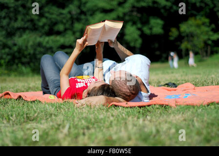 Schöne, glückliche Paar haben Picknick und Lesung außerhalb Stockfoto