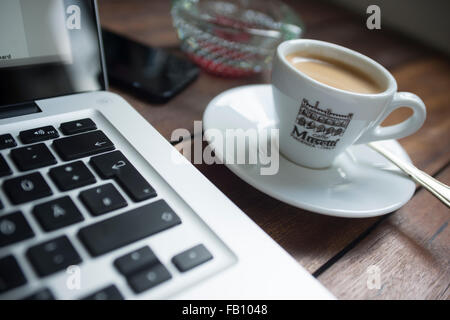 Espresso-Kaffee auf eine Designer-Schreibtisch platziert neben einem Laptop-Computer und Handy in einem Heim Arbeitsumfeld. Stockfoto