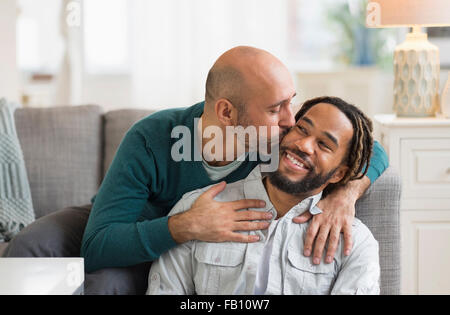 Homosexuelles Paar küssen vom Sofa im Wohnzimmer Stockfoto