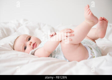 Babymädchen (12-17 Monate) auf Bett liegend Stockfoto