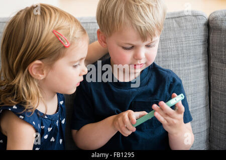 Bruder mit Schwester (2-3) spielt mit Ihrem Smartphone Stockfoto