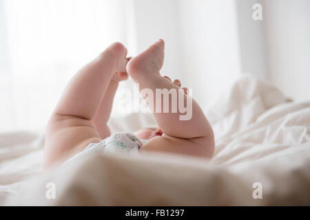 Babymädchen (12-17 Monate) mit Beinen oben liegend Stockfoto