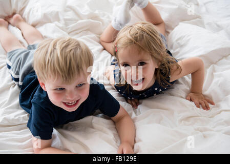 Bruder (2-3) mit Schwester (2-3) auf Bett liegend Stockfoto