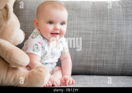 Babymädchen (12-17 Monate) mit Teddybär auf sofa Stockfoto