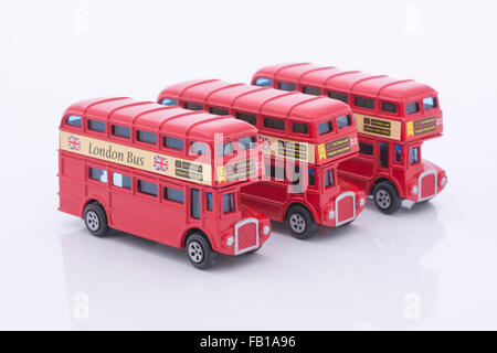 Drei Spielzeug (Druckguss) Londoner Busse aufgereiht. Metapher für die Erkundung Londons, in London arbeiten, London & Pendeln. Stockfoto