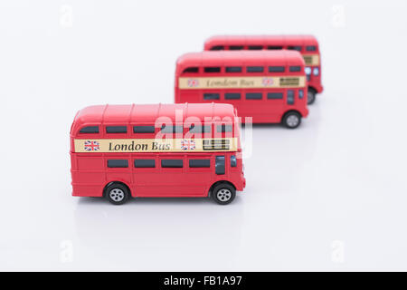 Drei Spielzeug (Druckguss) Londoner Busse aufgereiht. Metapher für die Erkundung Londons, in London arbeiten, London & Pendeln. Stockfoto