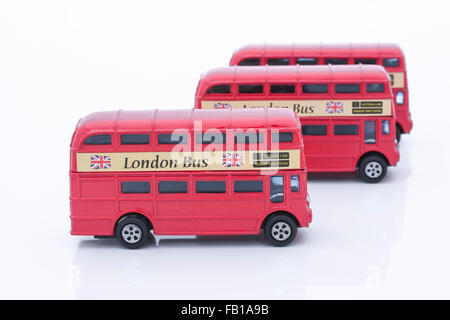 Drei Spielzeug (Druckguss) Londoner Busse aufgereiht. Metapher für die Erkundung Londons, in London arbeiten, London & Pendeln. Stockfoto