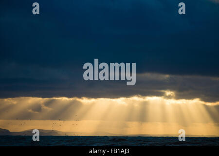 Aberystwyth Wales UK, Mittwoch, 7. Januar 2015 UK Wetter: dramatische Sonnenstrahlen brechen durch die dunklen Wolken, wie die Sonne über Cardigan Bay an der Westküste von Wales auf einem kalten windigen Januar Winter am Nachmittag Foto Credit untergeht: Keith Morris/Alamy Live News Stockfoto