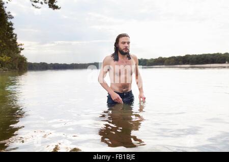 Junger Mann stehend in See Stockfoto