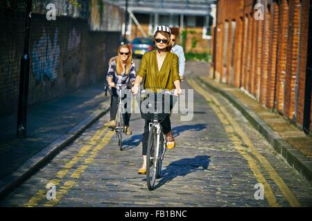 Vorderansicht der Frauen Sonnenbrille Fahrrad auf gepflasterten Straße Stockfoto