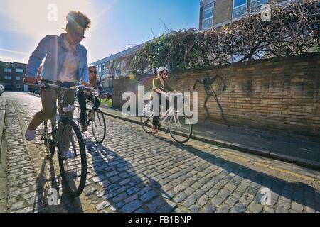 Seitlicher Blick auf Frauen auf Fahrrädern auf gepflasterten Straße Radfahren Stockfoto