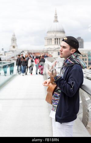 Junger Mann als Straßenmusikant auf Millennium Bridge, London, UK Stockfoto