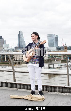 Junger Mann als Straßenmusikant auf Millennium Bridge, London, UK Stockfoto