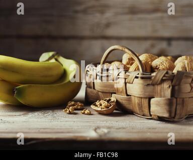 Bio-Bäckerei Zutaten, Weidenkorb mit Walnüssen und Bündel Bananen Stockfoto