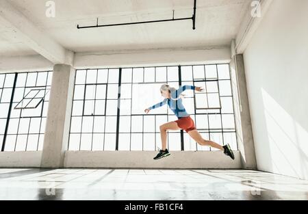 Seitenansicht der junge Frau im Fitnessstudio tun starke Mitte Luft laufen Haltung Stockfoto
