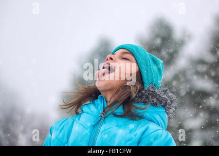 Mädchen nachschlagen, Zunge Schneeflocken fangen Stockfoto