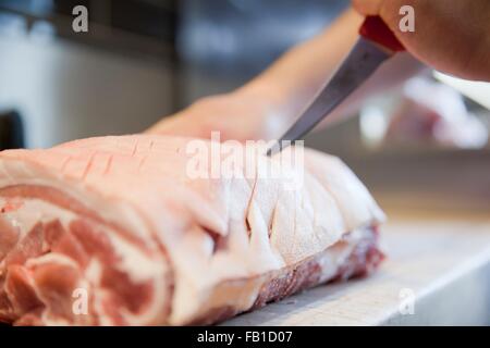 Nahaufnahme von Metzger Hand scoring Fleisch Gelenk im Metzger-shop Stockfoto