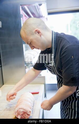 Jungen Metzger binden Fleisch Gelenk im Metzger-shop Stockfoto