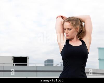 Junge Frau tut Aufwärm-Training auf Parkplatz Stockfoto