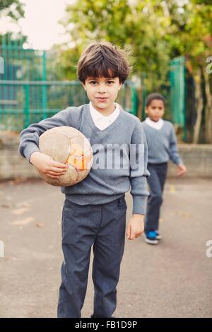 Porträt von elementaren Schuljunge mit Fußball Ball auf Spielplatz Stockfoto