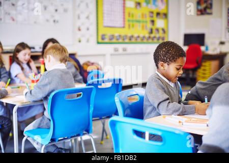 Kinder, die Zeichnung an Schreibtischen in Grundschule Klasse Stockfoto