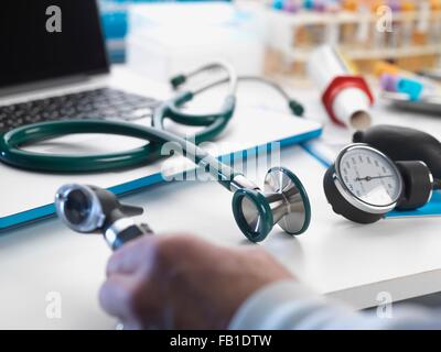 Arzt, Kommissionierung bis Auriscope mit Stethoskop und Blutdruck messen vom Schreibtisch Stockfoto