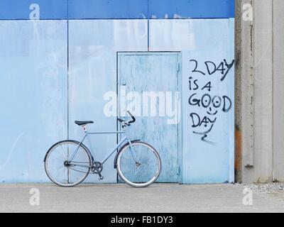 Fahrrad gegen Graffitiwand geparkt Stockfoto