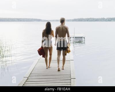 Rückansicht des Paares tragen Badeanzüge, hinunter Pier mit Handtüchern, Kopenhagen, Dänemark Stockfoto