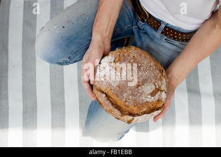 Draufsicht der Reife Frau auf gestreiften Teppich halten frisches gebackenes Brot Stockfoto