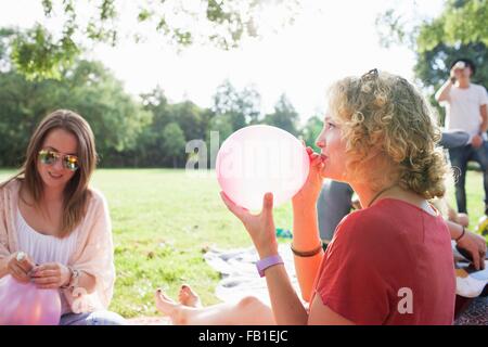 Junge Frau, die Sprengung Ballon auf Park-party Stockfoto