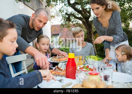 Vater und Teenager-Mädchen Kinderhilfe am Grill im Garten Tisch Stockfoto