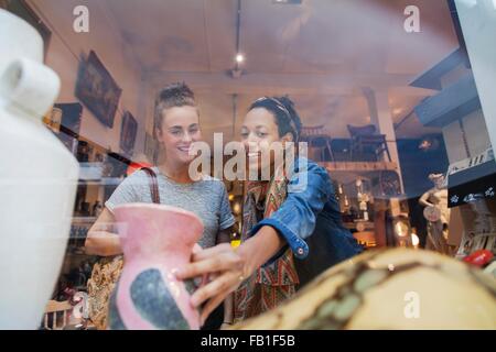 Junge Frau für rosa Vase in Vintage-Shop einkaufen Stockfoto