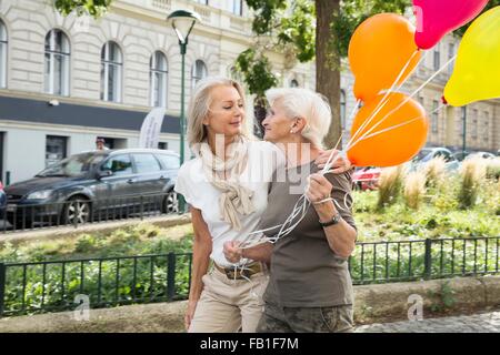 Mutter und Tochter zu Fuß entlang der Straße zusammen, halten Haufen Luftballons Stockfoto