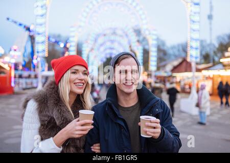 Glückliches junges Paar trinken Glühwein am Xmas Festival, Hyde Park, London, UK Stockfoto