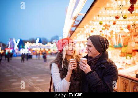 Junges Paar trinken Glühwein am Xmas Festival, Hyde Park, London, UK Stockfoto