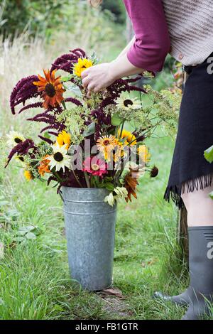 Blick auf Reife Frau arrangieren Blumen in Eimer bei Zuteilung beschnitten Stockfoto