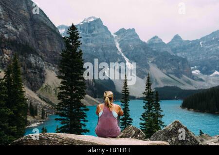 Rückansicht der Mitte Erwachsene Frau auf Klippe erhöhten betrachten der Moraine Lake, Banff Nationalpark, Alberta Kanada Stockfoto