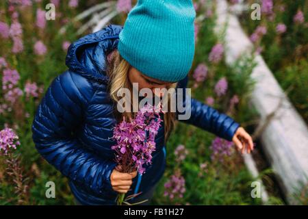 Vogelperspektive Ansicht Mitte Erwachsene Frau mit gepolsterten Mantel stricken Hut hält Wildblumen Moraine Lake Banff Nationalpark Alberta Kanada Stockfoto