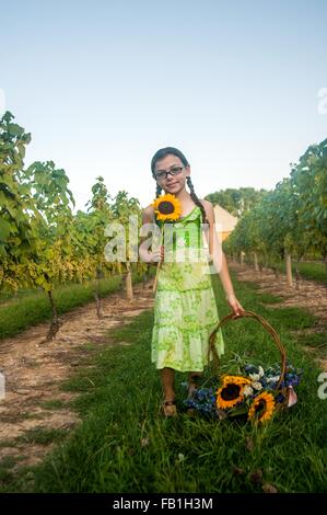 Porträt des jungen Mädchens mit Sonnenblume und Korb mit Blumen Stockfoto