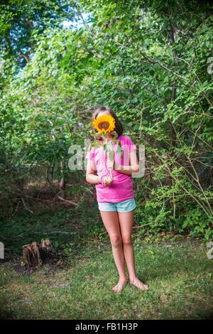 Junges Mädchen mit Sonnenblume vor Gesicht Stockfoto
