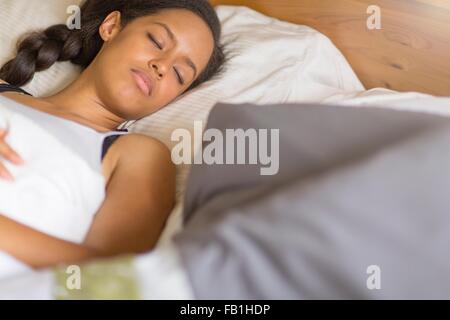 Erhöhte Ansicht der jungen Frau liegt auf zurück in geschlossenen Augen Bett schlafen Stockfoto