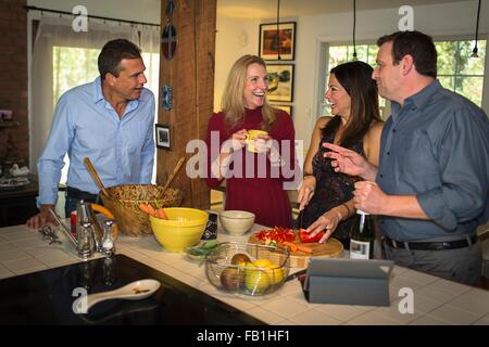 Zwei ältere Ehepaare, die Zubereitung von Speisen beim Abendessen feiern Stockfoto